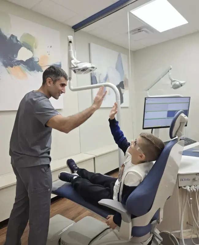 Dr. Komforti high-fiving young patient
